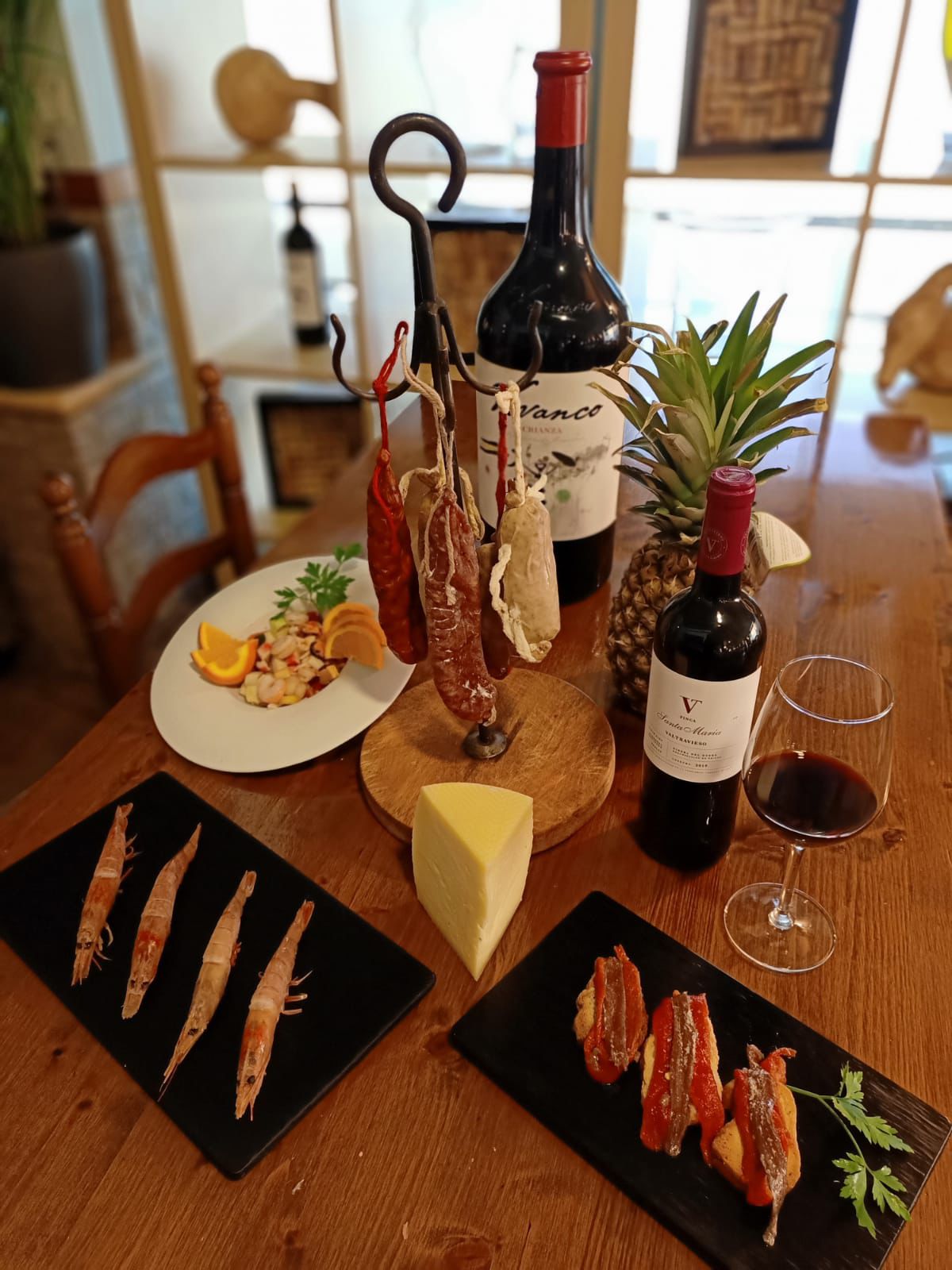 La Vaquería — mesa con embutidos, gambas, vinos y quesos